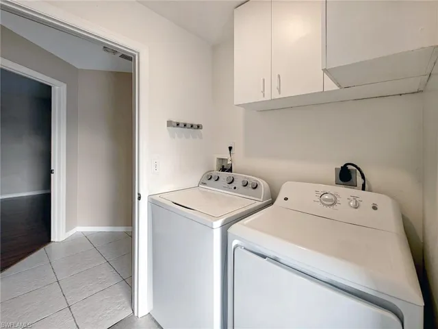 Washroom featuring independent washer and dryer, baseboards, light tile patterned floors, and cabinet space