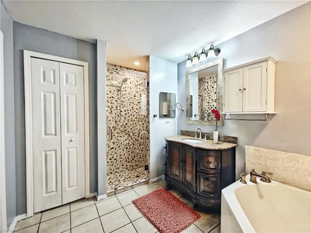 Bathroom featuring vanity, a shower stall, tile patterned flooring, and a garden tub
