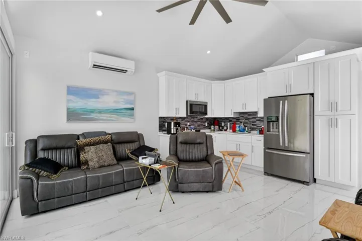 Living room with a ceiling fan, light marble finish flooring, and a wall mounted mini split
