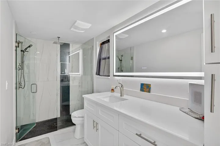 Full bathroom with vanity, a marble finish shower, and light marble finish floors