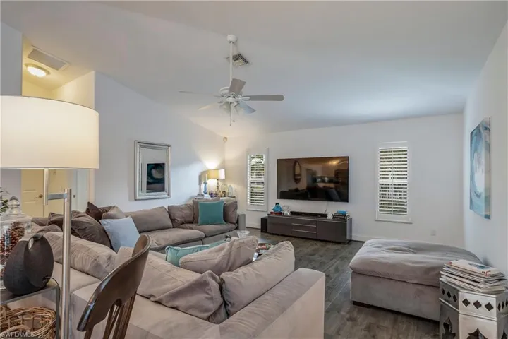 Living room with a ceiling fan, dark wood finished floors, plenty of natural light, and lofted ceiling