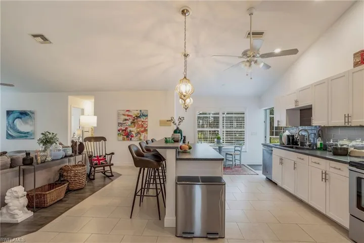 Kitchen featuring ceiling fan, dark countertops, appliances with stainless steel finishes, vaulted ceiling, and tasteful backsplash