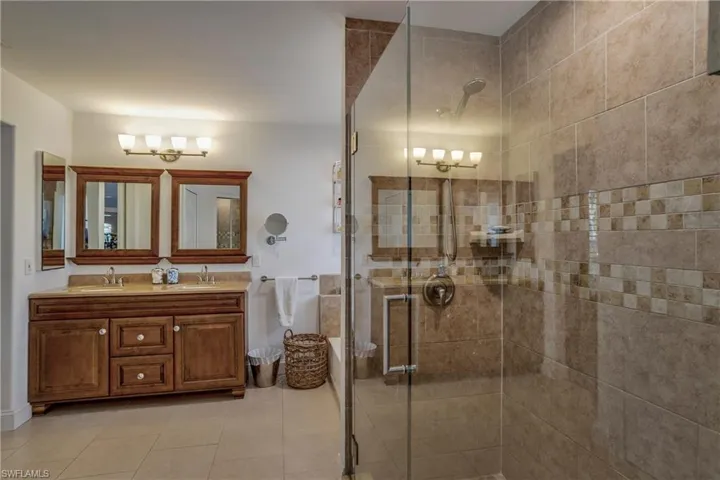 Full bath featuring a stall shower, double vanity, tile patterned floors, and a chandelier