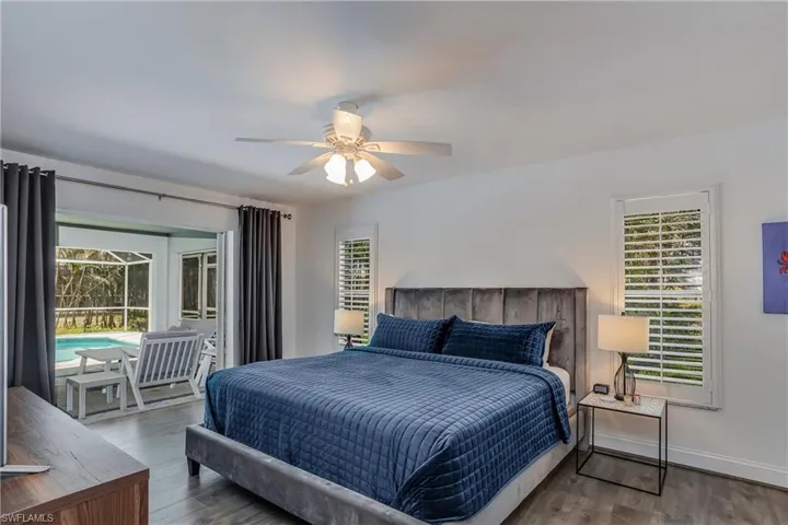 Bedroom featuring access to exterior, multiple windows, wood finished floors, and a ceiling fan