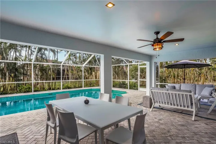 View of swimming pool with outdoor lounge area, a patio area, a ceiling fan, glass enclosure, and outdoor dining area