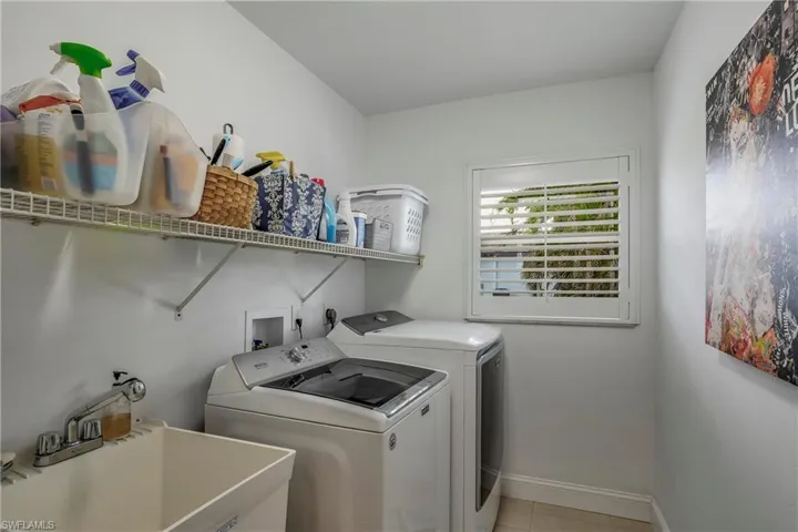 Laundry area with washing machine and dryer and light tile patterned floors