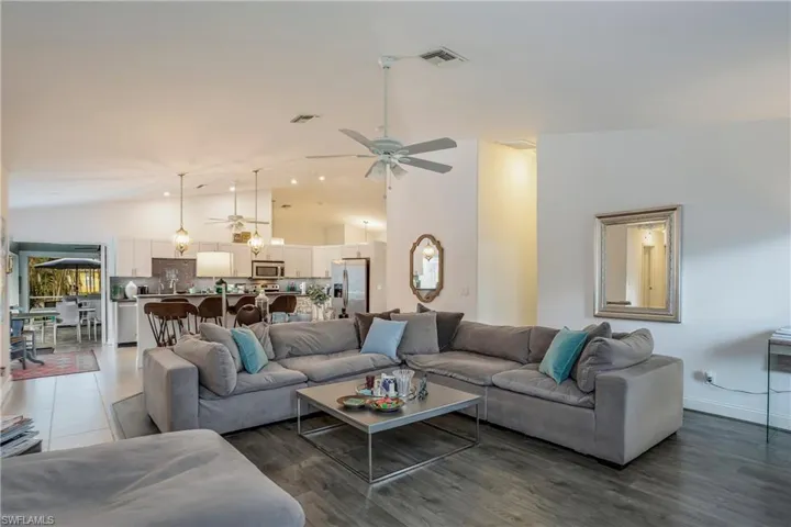 Living area with a ceiling fan, high vaulted ceiling, and wood finished floors