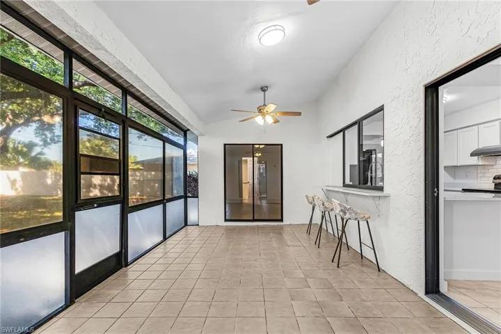 Screened porch with tile flooring and a ceiling fan