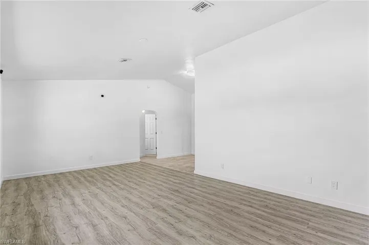 Spacious room with wood-finish flooring, vaulted ceiling, and recessed lighting