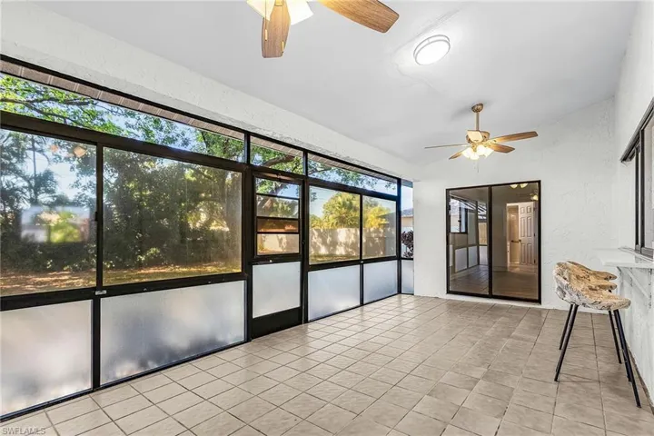 Screened patio featuring tile flooring and two ceiling fans