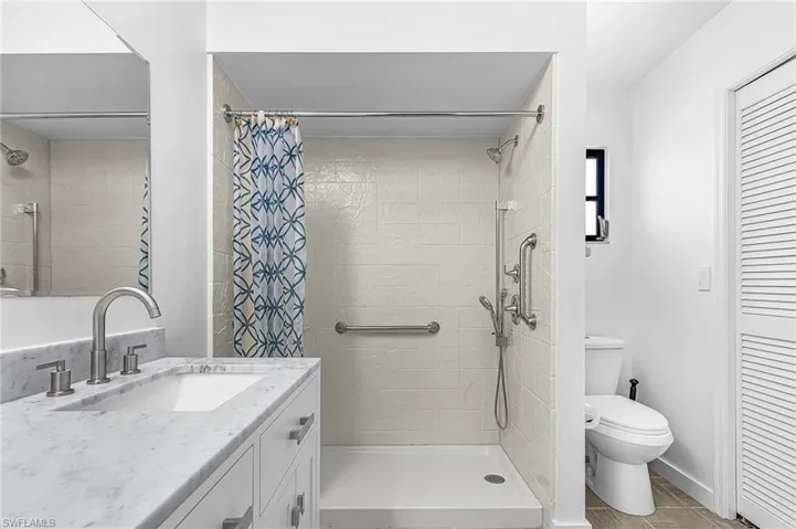 Contemporary bathroom featuring a walk-in shower with grab bars and a handheld showerhead