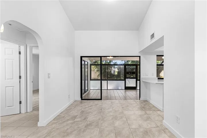 Spacious interior featuring high vaulted ceilings, light-toned tile flooring, and an expansive screened enclosure with exterior views