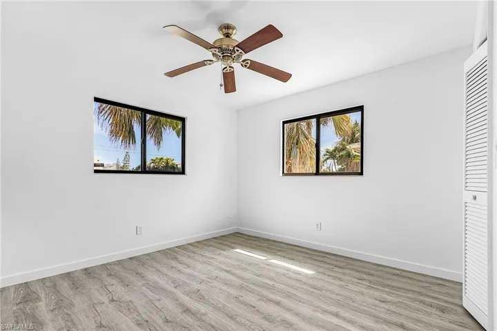 Bright interior space featuring wood-finish flooring, a ceiling fan, and white walls