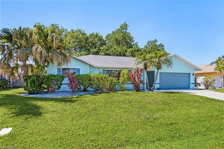 Single-story residence featuring a light blue exterior, attached two-car garage, and a manicured lawn