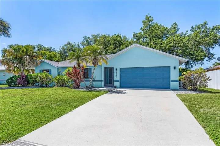 Single-story residence featuring a two-car garage, concrete driveway, and a vibrant blue exterior