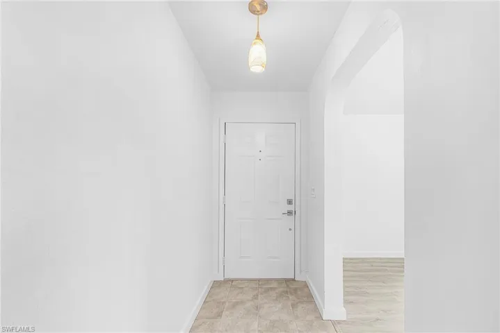 Entryway featuring a decorative pendant light, a white paneled front door, and tiled flooring