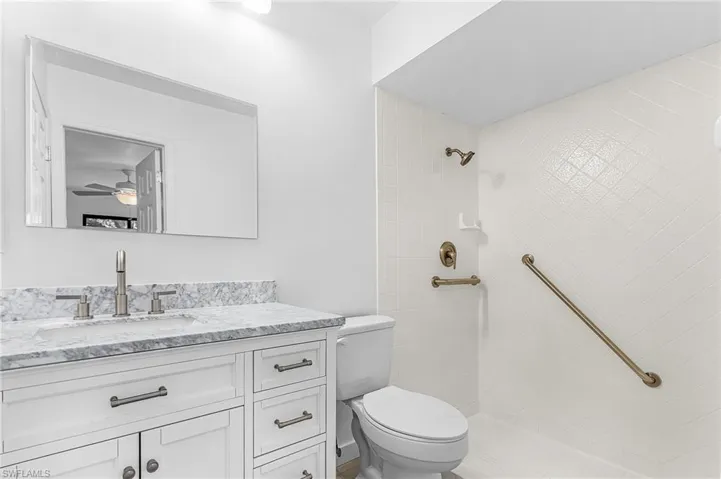 Bathroom featuring a white vanity with a stone countertop, an undermount sink, and brushed nickel fixtures