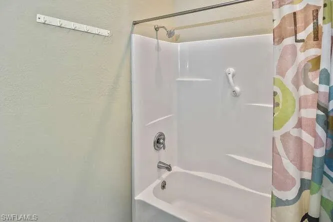 Full bathroom with shower / bath combo and a textured wall