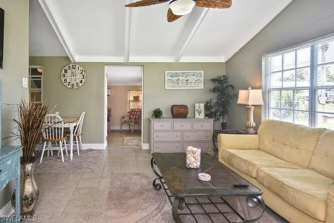 Tiled living room with ceiling fan and baseboards