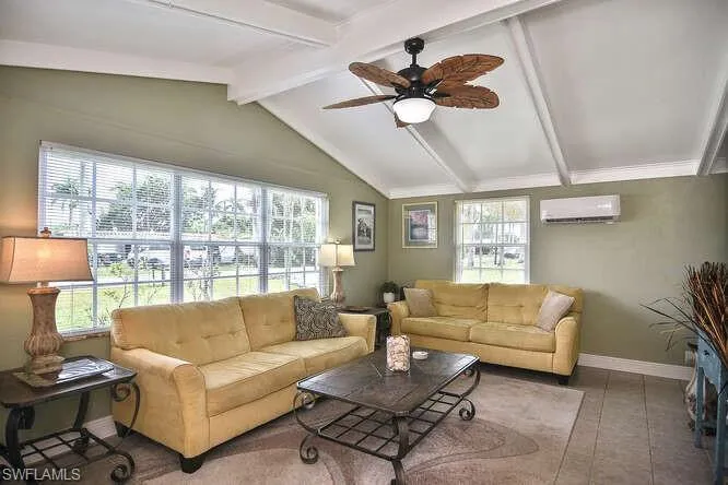 Living room with plenty of natural light, a ceiling fan, a wall unit AC, and tile patterned flooring