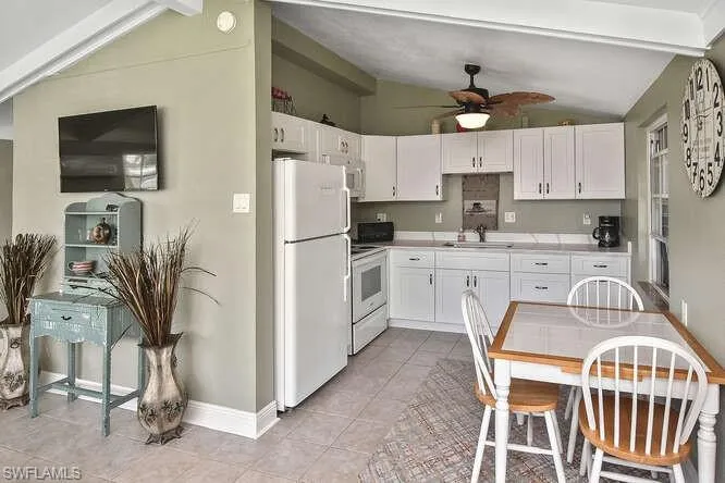 Kitchen with white appliances, white cabinets, ceiling fan, light tile patterned flooring, and light countertops