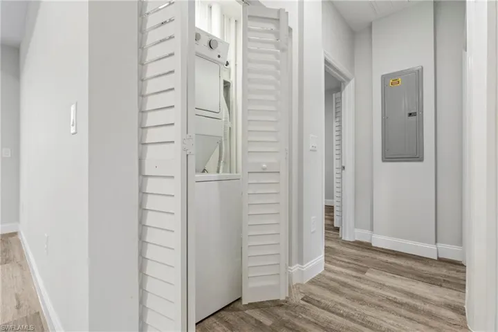 Hall featuring electric panel, light wood-type flooring, and stacked washer / dryer