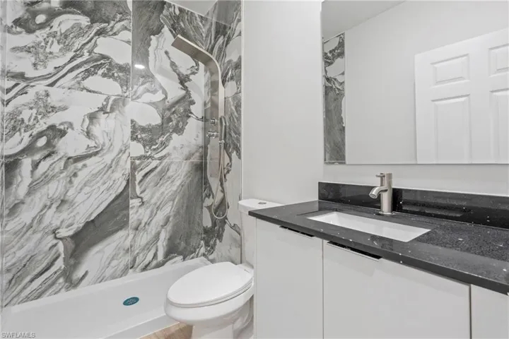 Bathroom featuring a marble finish shower and vanity