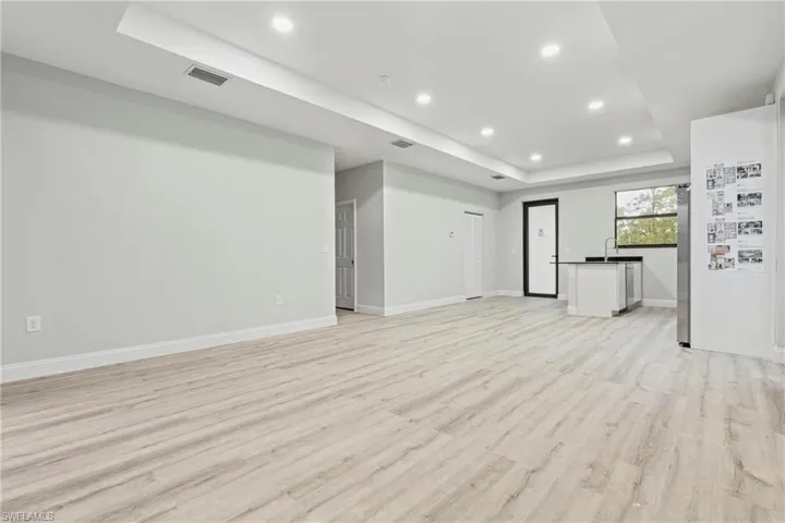 Unfurnished living room with recessed lighting, a tray ceiling, and light wood-style floors