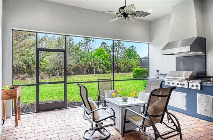 Sunroom / solarium featuring an outdoor kitchen / dining area, ceiling fan, and a patio
