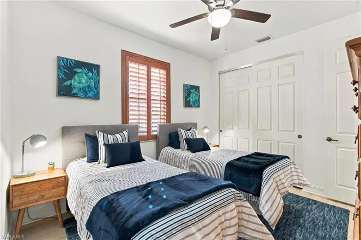 Room featuring a central ceiling fan with integrated lighting, wood-finish plantation shutters, and a multi-panel sliding closet door