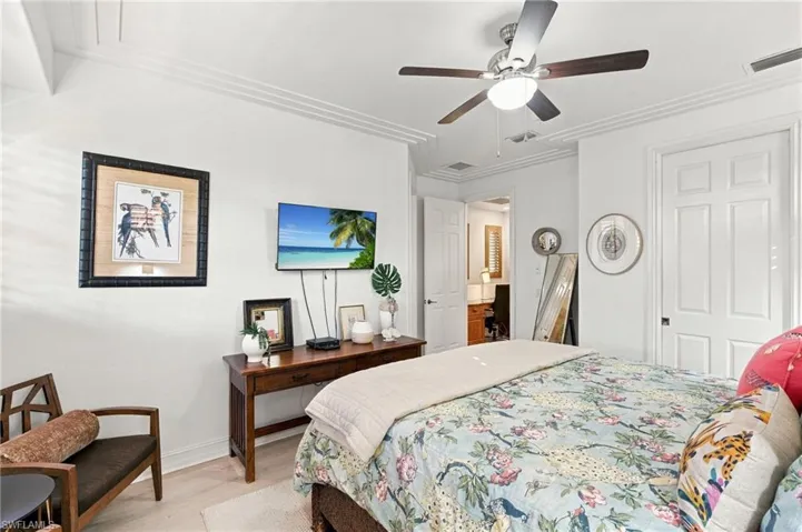 Interior space featuring crown molding, neutral wall finishes, wood-finish flooring, and a ceiling-mounted fan with integrated lighting