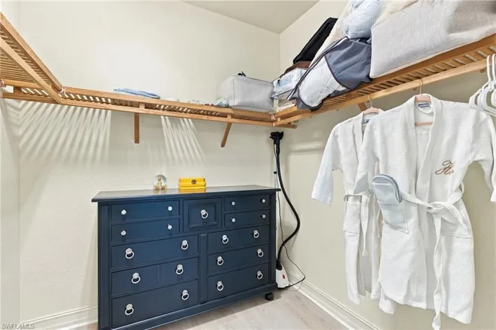 Walk-in closet featuring tiered natural wood shelving and a dedicated hanging rod
