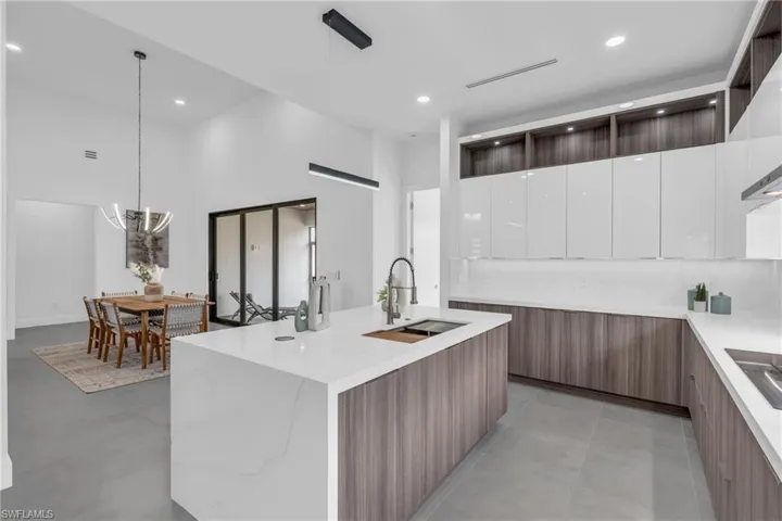 Kitchen with sink, pendant lighting, light tile patterned floors, a kitchen island with sink, and white cabinetry