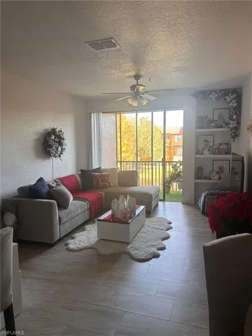 Living room featuring healthy amount of natural light, a textured ceiling, and a ceiling fan
