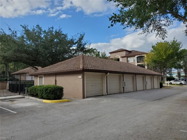 View of property exterior with a tiled roof, community garages, and stucco siding