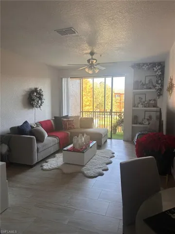 Living area featuring a ceiling fan and a textured ceiling