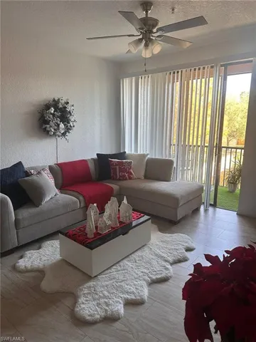 Living area with healthy amount of natural light, a ceiling fan, a textured ceiling, and wood finished floors