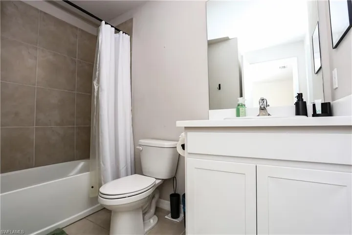 Full bathroom featuring light tile patterned floors, shower / bath combo with shower curtain, and vanity