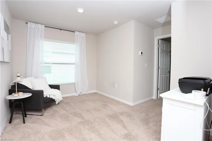 Sitting room with light colored carpet and baseboards