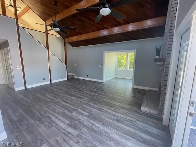 Unfurnished living room featuring dark wood-style floors, a fireplace, wood ceiling, and a ceiling fan