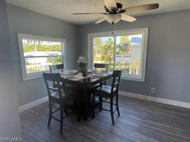 Dining space with a textured ceiling, dark wood-style flooring, and a ceiling fan