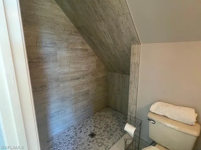 Bathroom featuring tiled shower and toilet