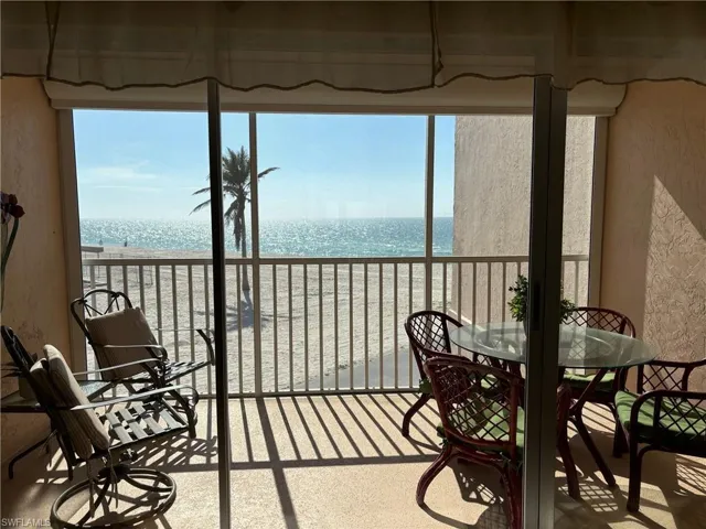 Sunroom featuring a healthy amount of sunlight, a water view, and a view of the beach
