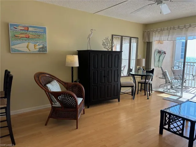 Living area with ceiling fan, a textured ceiling, and light wood-type flooring