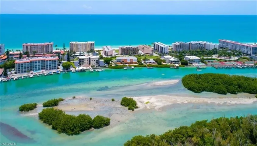 Birds eye view of property with a water view and a beach view