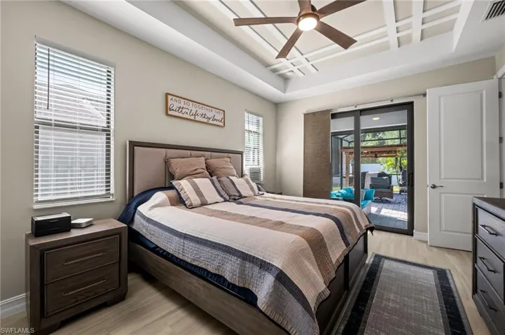 Bedroom featuring access to outside, light wood-style flooring, coffered ceiling, multiple windows, and a ceiling fan