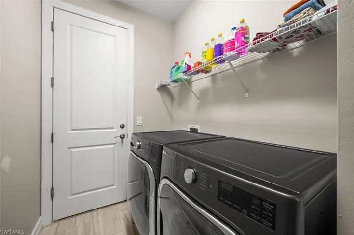 Laundry room with washing machine and dryer and light wood-style flooring