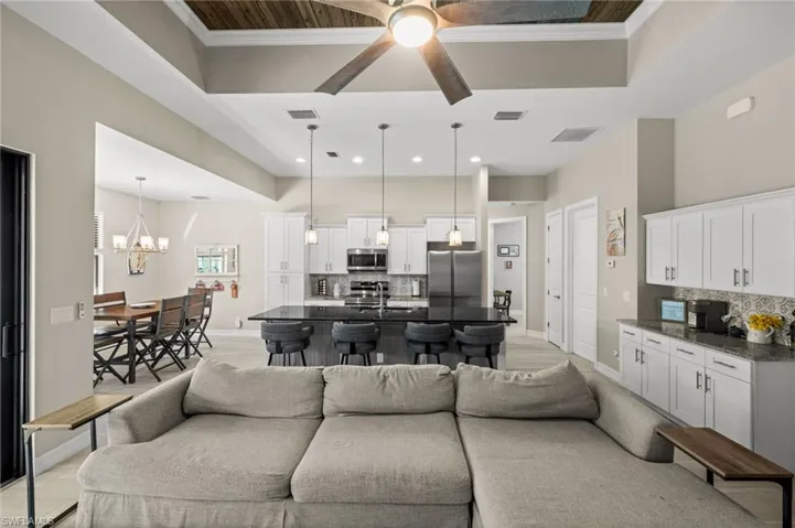 Living area featuring ornamental molding, a chandelier, a ceiling fan, and a high ceiling