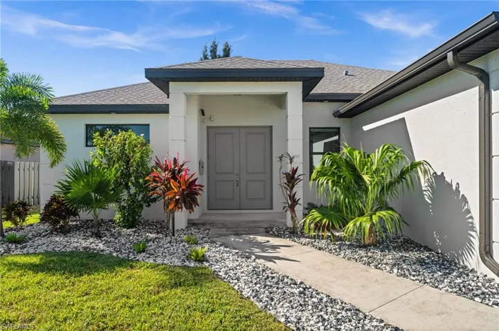 Doorway to property with a shingled roof and stucco siding