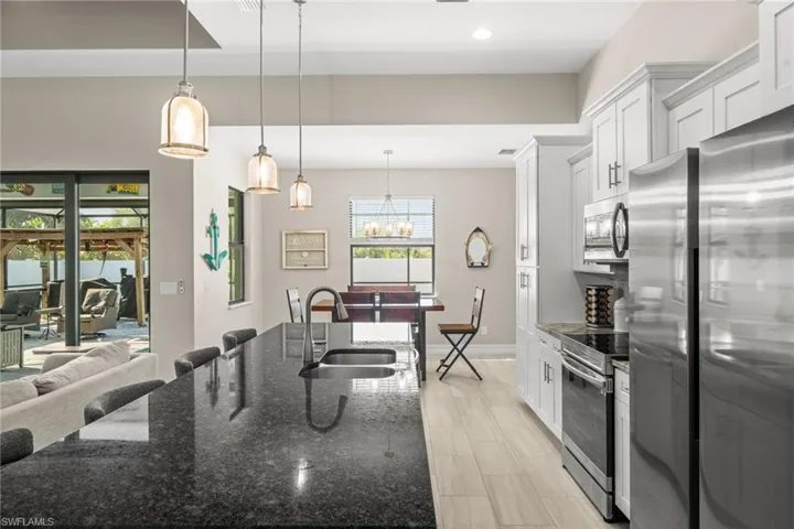 Kitchen with dark stone counters, pendant lighting, a breakfast bar area, stainless steel appliances, and white cabinets
